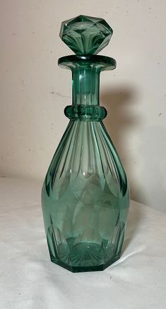 a green glass vase sitting on top of a white table