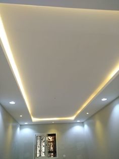 an empty room with white walls and lights on the ceiling is lit by recessed lighting