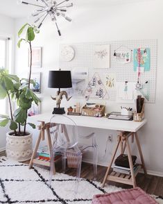 a white desk topped with a chair next to a potted plant