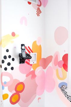 a phone is sitting on top of a microwave in a room with colorful wallpaper