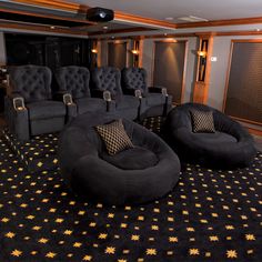 an empty theater with black chairs and gold stars on the carpet, in front of a wall mounted projector screen