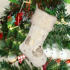 a stocking hanging from a christmas tree decorated with ornaments and baubles on it