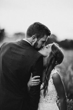 a bride and groom kissing in a field