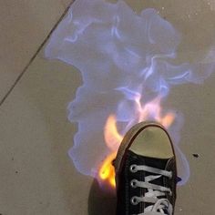 a pair of black sneakers with white laces on them are burning in the floor