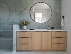 a bathroom with a sink, mirror and bathtub in the background is tiled walls