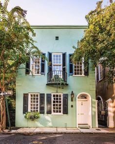 a green house with black shutters and white doors on the street in front of it