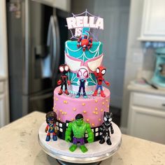 a birthday cake decorated with superheros and spider - man figurines