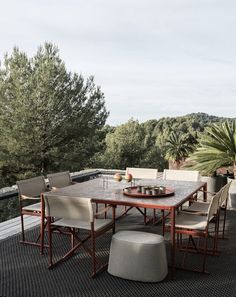 a table and chairs on a deck with trees in the backgroung area