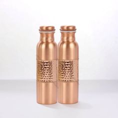 two copper colored bottles sitting next to each other