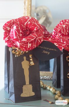 two black bags with red bows on them and some gold decorations in front of them