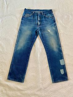 "Beautifully distressed vintage Rustler denim jeans. Incredible natural fading and stacking/whiskering. Wallet wear on back butt pocket. Unique patches toward bottom of left pant leg. A few tears but nothing that runs all the way through; only adds to the character and coolness. These are truly amazing. Buttery soft broke-in 100% cotton denim - the best! Tag size has been worn off but measures to a 35x31. See exact measurements to be sure of fit. Measurements: waist: 17.5\" hip: 22\" rise: 12.5\" inseam: 31\"" Vintage Distressed Blue Jeans, Rugged Faded Rigid Denim Jeans, Vintage Washed Blue Recycled Denim Jeans, Vintage Washed Blue Jeans In Recycled Denim, Ripped Vintage Jeans In Recycled Denim, Vintage Ripped Jeans In Recycled Denim, Vintage Washed Blue Distressed Jeans, Vintage Faded Rigid Denim Jeans, Vintage Style Faded Rigid Denim Jeans