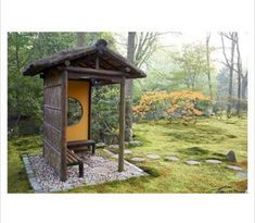 an outhouse in the middle of a grassy area with rocks and grass around it