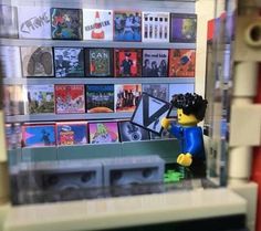 there is a lego man that is standing in front of a shelf full of cds