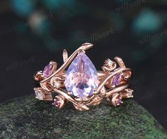 a ring with an amethorate and pink stones on it sitting on top of a rock