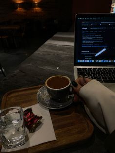 a person sitting at a table with a laptop and cup of coffee in front of them