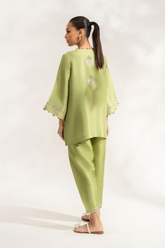 Siran (B) reinterprets the classic shalwar kameez with its box cut front open pure rawsilk shirt in a sage green hue. The subtle combination of ivory, lavender, and lilac embroidery elevates the shirt and the hem of the pure rawsilk shalwar.Model Height: 5'6 Length: 29" Green Silk Salwar Kameez For Formal Occasions, Formal Green Lawn Suit With Dabka Work, Formal Long Sleeve Palazzo Set With Naqshi Embroidery, Formal Long Sleeve Palazzo Set With Naqshi Detail, Formal Long Sleeve Palazzo Set With Naqshi, Green Silk Unstitched Suit For Formal Occasions, Formal Green Silk Unstitched Suit, Formal Pista Green Sets With Chikankari Embroidery, Formal Green Lawn Suit With Long Sleeves