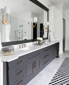 a large bathroom with black and white tile flooring, two sinks and mirrors on the wall