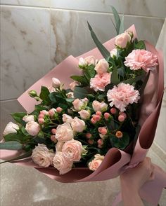 a bouquet of pink and white flowers sitting on top of a marble counter next to a tiled wall