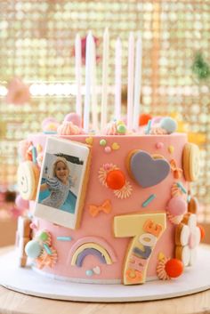 a pink birthday cake with pictures and candles on the top is sitting on a table