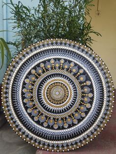 a decorative black and white plate sitting on top of a cement slab next to a plant