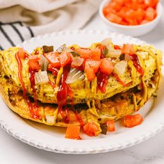 two omelets on a white plate with carrots and ketchup drizzled over them