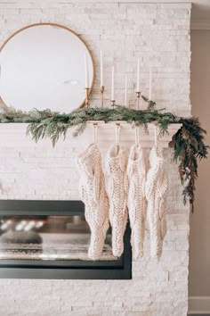 stockings hanging from a mantle in front of a fireplace with candles and greenery on it