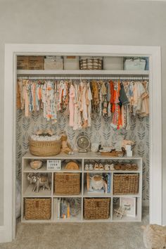 an organized closet with baskets and clothes hanging on the wall, next to a teddy bear