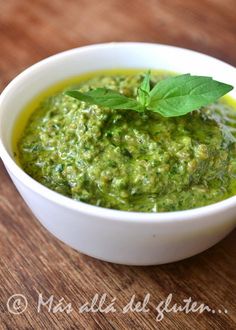 a white bowl filled with green sauce on top of a wooden table