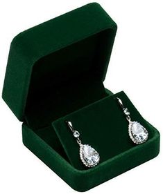 a pair of earrings in a green velvet box on a white background with clippings