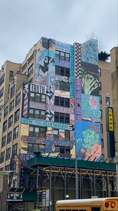 a yellow bus driving past a tall building covered in graffiti