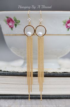 "Gorgeous new earrings made using 14K gold plated components, and faux pearl. The earrings feature circle links, with a white faux pearl at the bottom. They connect to various pieces of long gold chain, that graduate in length. All hang from 14K gold plated hook ear wires, with prong set square CZ jewels. Total earring length is 3 3/4\" long. Distance from tip of ear wire to bottom of circle is roughly 1\". Lightweight, yet not short on style!  * Nickel and lead free" Pearl Chain Round Metal Earrings, Party Gold Hoop Earrings With Pearl Chain, Gold Hoop Earrings With Pearl Chain For Party, Gold Chandelier Earrings With Pearl Drop, Gold Round Linear Pearl Drop Earrings, Gold Linear Earrings With Pearl Chain For Party, Gold Plated Round Chandelier Earrings, Pearl Earrings Long, Long Chain Earrings