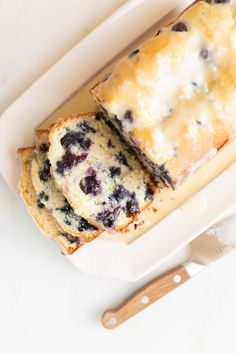 two slices of blueberry bread in a white dish with a wooden spoon next to it