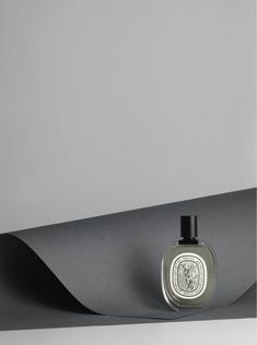 a bottle of cologne sitting on top of a black piece of paper that is hanging from the ceiling