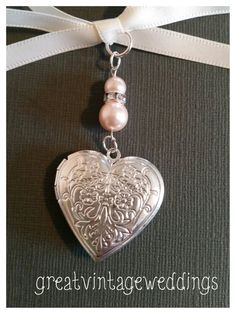 a heart shaped locke with pearls hanging from it's side on a white ribbon