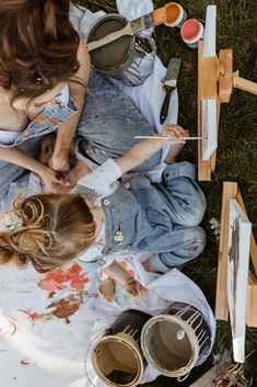 two girls are painting on the ground with paintbrushes