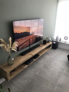 a large flat screen tv sitting on top of a wooden entertainment center next to a window