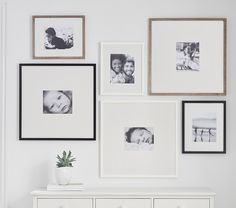 a white dresser topped with lots of framed pictures