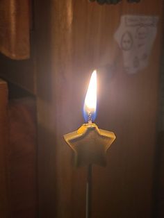 a small candle is lit in front of a wooden wall with the light shining on it