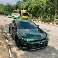 a green car is parked on the side of the road near a double decker bus