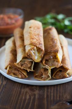 two burritos on a plate with salsa in the background