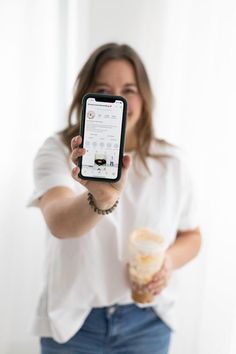 a woman in white shirt holding up a cell phone