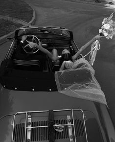 a bride and groom sitting in the back of a convertible car