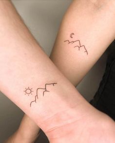 two people with matching tattoos on their arms, one is holding the other's arm