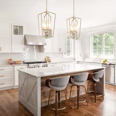 a kitchen island with four stools in front of it and three lights hanging from the ceiling