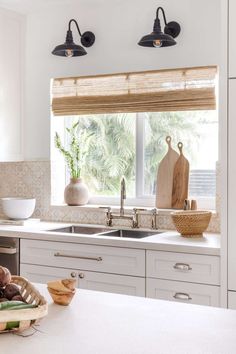 a kitchen with white cabinets and an island in front of a window that has bamboo shades on the windowsill