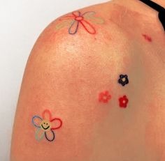 a woman's back with small tattoos on her arm and shoulder, which are colored in different colors