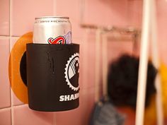 a can holder is hanging on the wall next to a pink tiled wall with black and white stickers