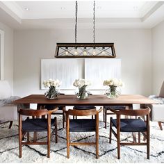 a dining room table with chairs and flowers in vases on the top of it