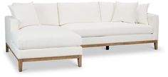 a white couch with pillows on top of it and a wooden foot rest in front of it