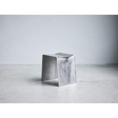 a square metal object sitting on top of a cement floor next to a white wall